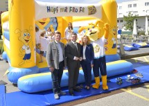 Vor der "Fito Fits"-Kinderhüpfburg: Johannes Zuser, Bürgermeister der Gesunden Gemeinde Hürm und Vater von drei Kindern, Landesrat Ludwig Schleritzko und Landesschulärztin Gabriele Freynhofer mit Maskottchen "Fito Fits" (v.l.n.r.)