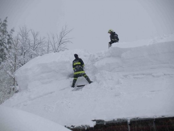 Feuerwehrmänner beim Abschaufeln eines schneebedeckten Daches
