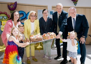 (v.l.) IZIBIZI-Leiterin Katja Ury, Landeshauptfrau Johanna Mikl-Leitner, Andrea Lautermüller, Leiterin WK Mödling, Philipp Enzinger, Bezirkshauptmann Mödling, und ecoplus Geschäftsführer Helmut Miernicki mit den IZIBIZI-Kids, die sich über die Torte zum 20. Jubiläum freuten.