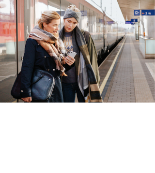 Zwei Frauen am Bahnsteig vor einem Zug
