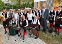 Landeshauptfrau Johanna Mikl-Leitner, Bezirkshauptmann Andreas Strobl (links), Abgeordneter Christian Gepp und der geschäftsführende Gemeinderat Mauritz Großinger (rechts) flankiert von den Mitgliedern der Blasmusikkapelle