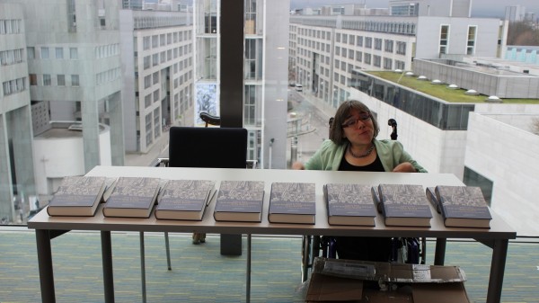 Sandra Hermann sitzt an einem Tisch mit Büchern von Andreas Nastl 