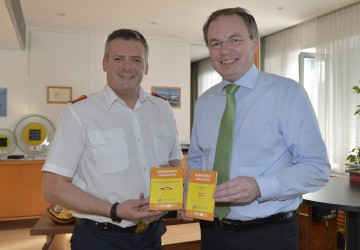 Landesrat Dr. Stephan Pernkopf und Landesfeuerwehrkommandant Dietmar Fahrafellner präsentieren Notfallhandbücher (v.l.n.r.).