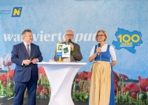 Wiens Bürgermeister Michael Ludwig, Moderator Andy Marek und Landeshauptfrau Johanna Mikl-Leitner im Gespräch auf der Bühne am Wiener Rathausplatz.
