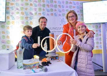 Landeshauptfrau Johanna Mikl-Leitner, Physiker Bernhard Weingartner und zwei junge Besucherinnen und Besucher des Forschungsfestes stellten anlässlich des 100-jährigen Jubiläums des Bundeslandes Niederösterreich auf experimentelle Weise die Zahl „100“ dar.