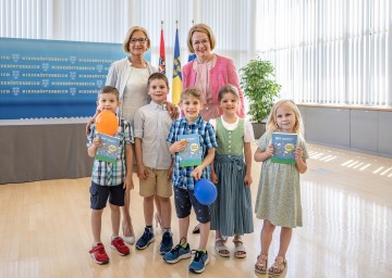 Landeshauptfrau Johanna Mikl-Leitner und Landesrätin Christiane Teschl-Hofmeister mit Kindern und dem „DIY Experimente Handbuch Sommer Edition“.