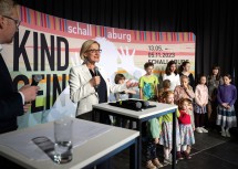 Landeshauptfrau Johanna Mikl-Leitner bei der Eröffnung der Ausstellung, auf der Bühne mit den Schülerinnen und Schülern der NMS Loosdorf.